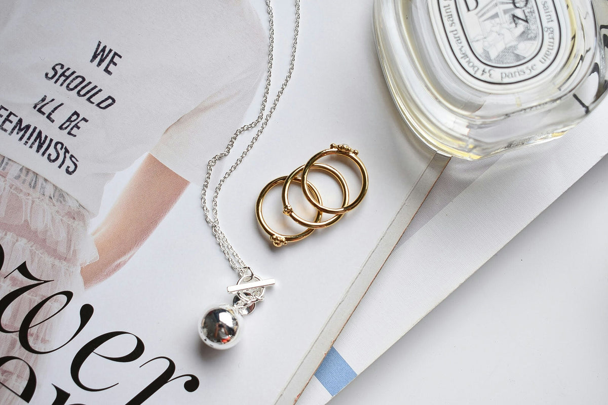 A 925 Italian Silver Chains resting on a book next to Stackable Rings.