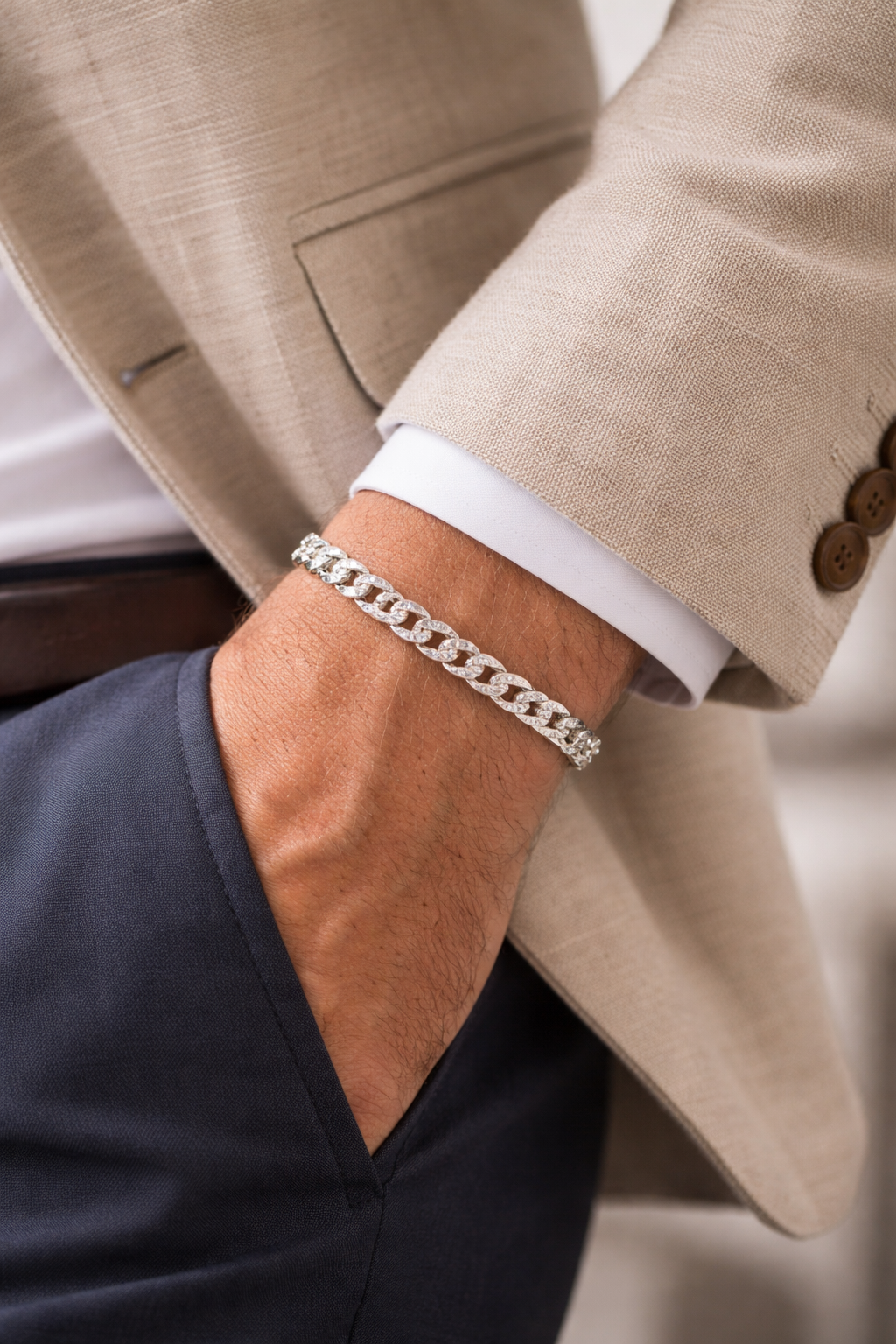 Close-up of a person wearing a Teddy Howler Curb SF Pavé Bracelet with a beige suit jacket and white shirt