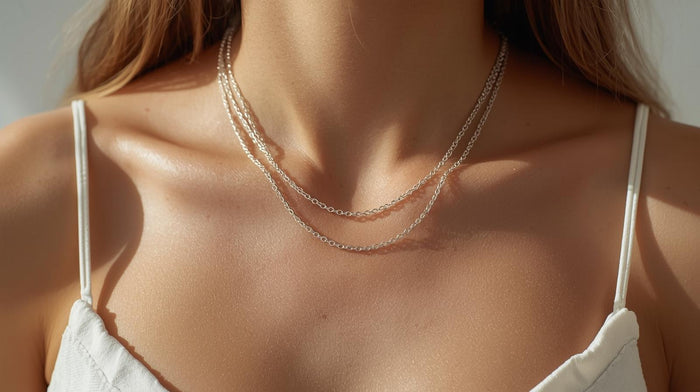 Woman wearing layered silver necklaces in different lengths with a white top.