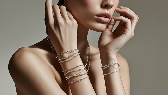 A woman styling multiple layered silver chain bracelets on both wrists, showcasing elegant bracelet stacking fashion.