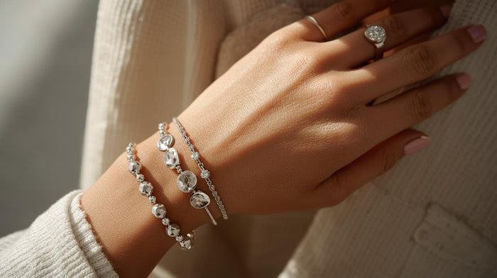 Stacked silver bracelets with gemstones and beads paired with rings, creating a chic layered jewelry style.