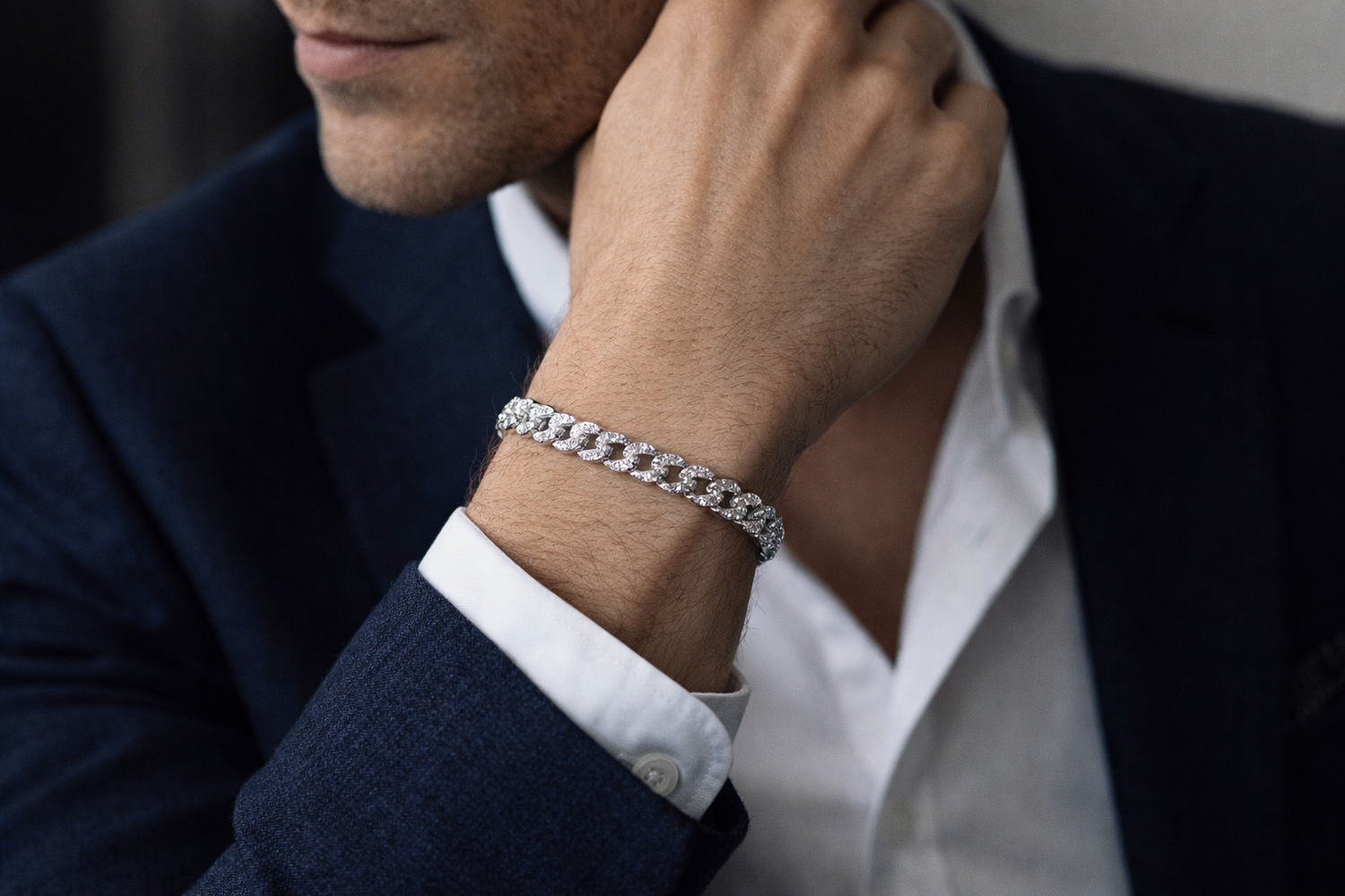 Man wearing a Teddy Howler Curb SF Pavé Bracelet  on his wrist, dressed in a dark suit and white shirt.