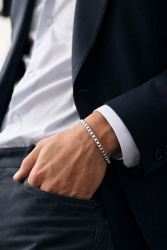 Person wearing a silver Teddy Howler box chain bracelet with a dark suit and white shirt