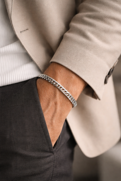 Close-up of a person earing a Teddy Howler double link chain bracelet with a neutral background