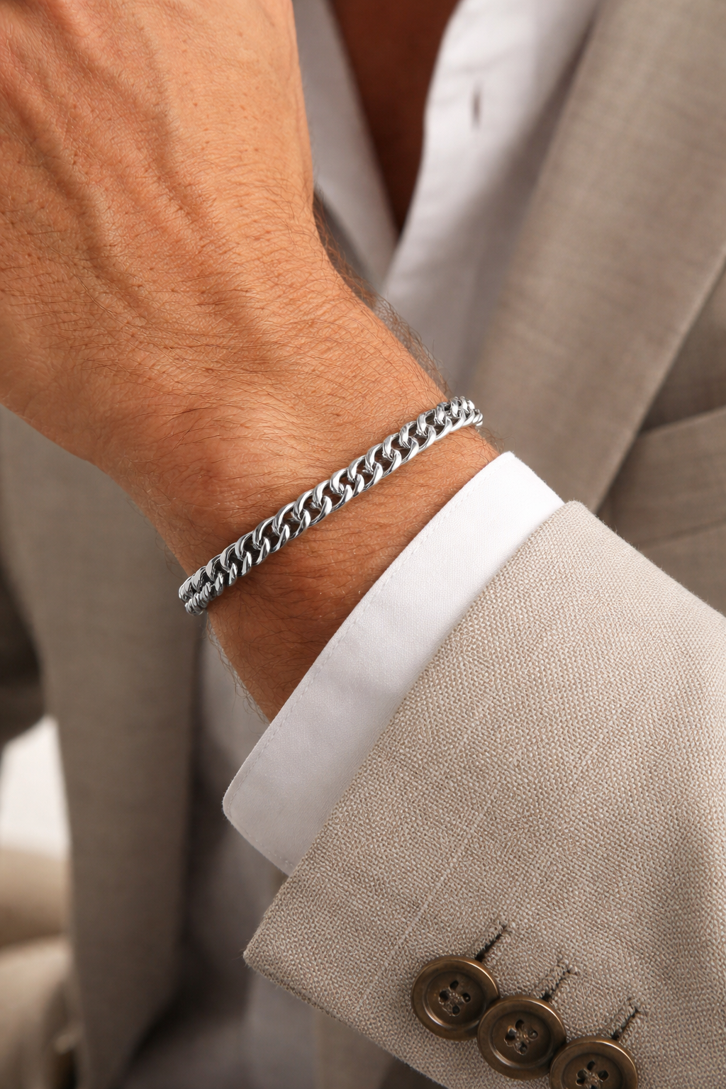 Close-up of a person wearing a Teddy Howler double link chain bracelet on a beige suit with a white shirt.