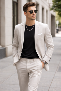 Man wearing a Teddy Howler hollow curb necklace and a light gray suit with a black shirt and sunglasses on a NY city street.