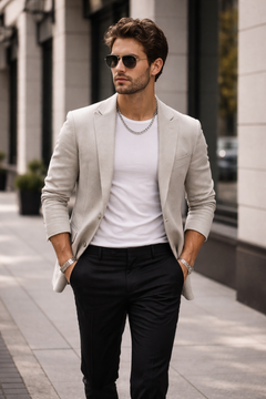 Man wearing a Teddy Howler Tiger Eye Italian Silver necklace and a light gray blazer, white shirt, and black pants on a city street.